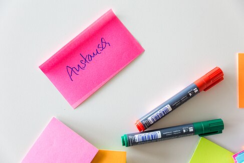 Post-It mit der Aufschrift Kontakt auf einem Tisch mit Stiften