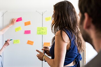 Frau klebt Post-Its an Whiteboard