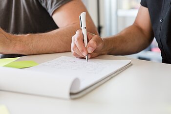 Hände schreiben auf Papier am Tisch
