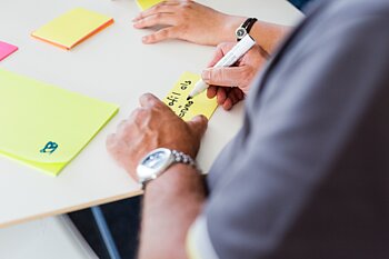 Hände schreiben auf Post-its
