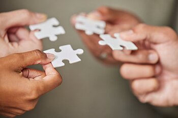 Hände halten vier Puzzleteile